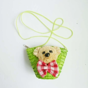 Detail of light green straw crossbody bag featuring a cute bear head with a checkered bow