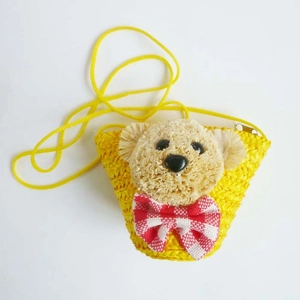 Detail of yellow straw crossbody bag featuring a 3D bear head and red plaid bow tie