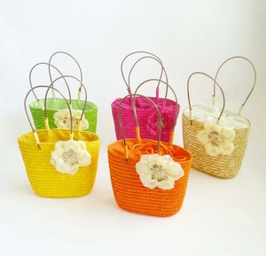 Group display of five colorful straw woven bags with flower details and drawstring lining