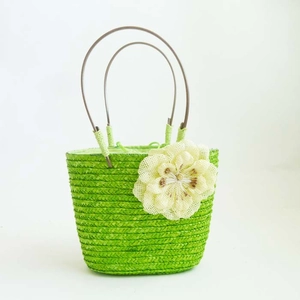 Detail of green straw handbag featuring circular handles and a 3D woven flower decor