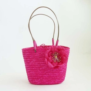 Close-up of vibrant pink woven straw bag with sequin accents and handmade floral detail