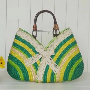 Handwoven straw beach bag with green yellow stripes and elegant lace bow detail