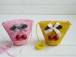 Detail of mini cherry straw crossbody bags in pink and yellow with bow accents