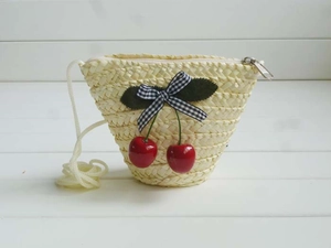 Detailed view of handmade straw coin purse with cherry charm and gingham ribbon bow