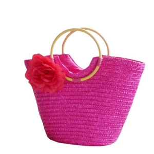 Pink straw woven beach tote bag with a large red flower and round wooden handles