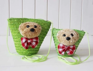 Detail of green straw woven bear bag featuring red checkered bow and zip closure
