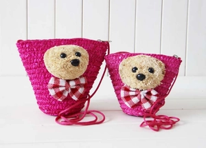 Detailed view of two rose pink straw woven bear crossbody bags with cute plush charms