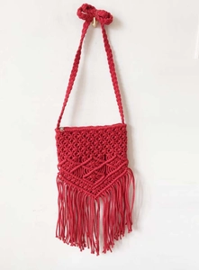 Detail of red macrame crossbody bag featuring bohemian fringe and intricate woven patterns