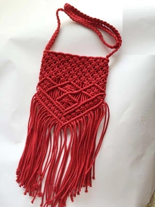 Macro shot of red handmade macrame tassel bag with intricate diamond weaving patterns
