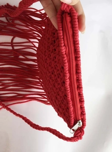 Close-up of red woven tassel bag showing zipper closure and detailed knit texture