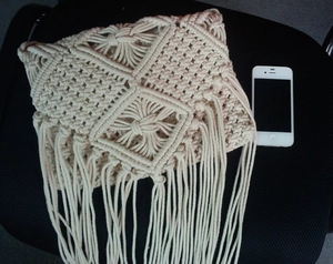 Detail view of cream handmade woven tassel bag with geometric patterns and fringe