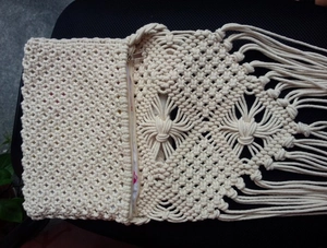Detail of bohemian ivory hand-woven bag featuring fringe tassels and metal zipper closure