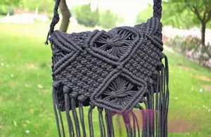 Detailed view of black macrame woven shoulder bag with intricate tassel fringe and geometric knit