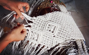 Detail of handmade macramé bag showing white cotton rope texture and fringe tassels