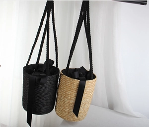 Detail view of woven straw bucket bags with black ribbon drawstring and rope handles