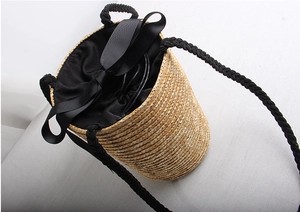 Detail of straw bucket bag with black ribbon bow and drawstring lining for beach style
