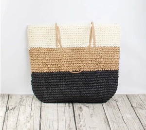 Close-up of color-block woven tote bag with natural straw texture and slim brown handles