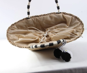 Detail of bohemian straw tote with drawstring lining and decorative pompom charm