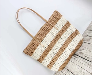 Detail of striped straw tote with brown leather straps and secure zipper closure