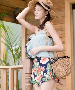 Summer vacation outfit detail with straw shoulder bag, pom poms and floral shorts