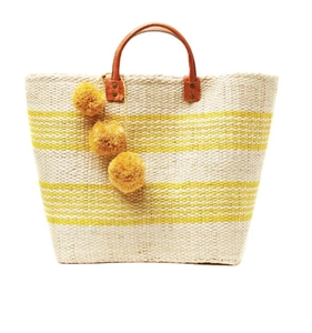 Detail of straw beach bag with yellow stripes, leather handles and decorative pom-poms