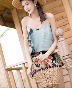 Straw woven shoulder bag styled with pom-pom detail for a summer beach vacation look