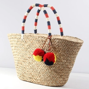 Bohemian woven straw tote bag with colorful handles and decorative pom-poms