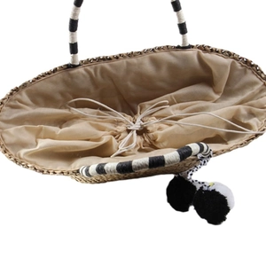 Bohemian woven straw tote bag with black and white pom-poms and drawstring closure