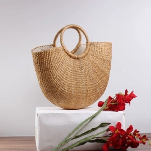 Minimalist straw beach bag with semi-circular woven body and round handles for summer style