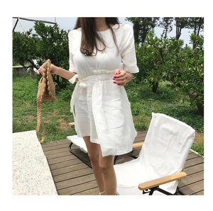 Detail of white crepe midi dress with drawstring waist and summer woven straw handbag