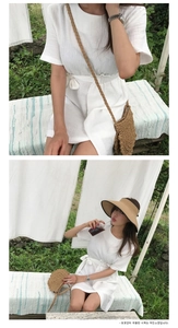 Detail of a minimalist straw round crossbody bag paired with a white summer dress