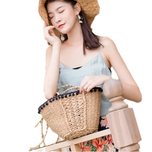 Handmade straw beach bag with black pom-poms and woven rope handles for summer vacation