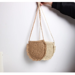 Detail of straw woven crossbody bags in caramel and cream with hollow wave lace edges