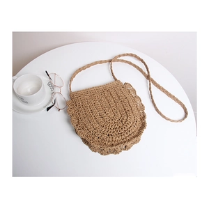 Minimalist semi-circular woven straw crossbody bag with scalloped edges and shoulder strap