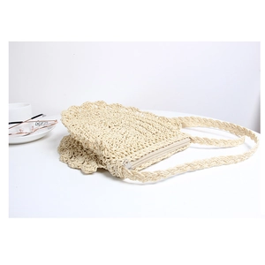 Detail view of cream straw crossbody bag with scalloped edges and woven shoulder strap