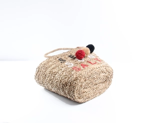 Detail of summer straw bag featuring colorful pom-poms and embroidered summer lettering