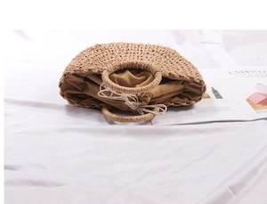 Close-up of a semi-circular straw handbag with round handles and a drawstring fabric lining