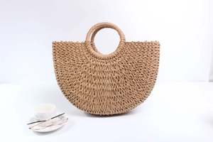 Detailed view of semi-circular straw woven handbag with circular top handles for summer