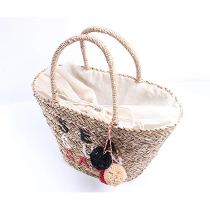 Handwoven straw beach bag with colorful letter embroidery and soft pompom charms