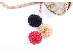 Detailed close-up of natural straw bag with colorful pom-poms and drawstring lining