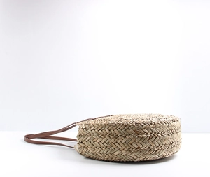 Detailed close-up showing the sturdy round straw weave and dark brown leather strap
