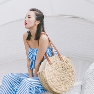 Detail of round straw beach bag showing spiral weaving texture and brown leather strap