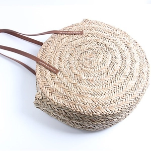 Large circular straw woven beach shoulder bag with brown leather straps for summer vacation