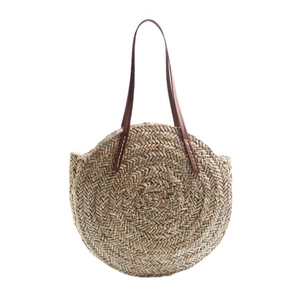 Handcrafted circular straw shoulder bag with leather handles for summer beach vacations