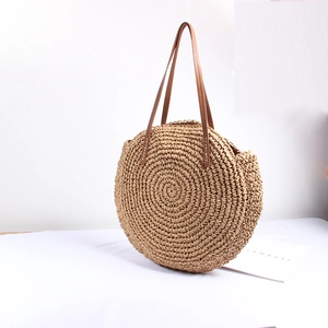 Detail of round straw tote with hand-woven textures and premium brown leather straps
