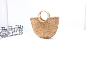 Detail of a semi-circular straw handbag with ring handles and woven mesh texture