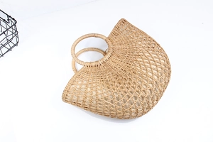 Detail of hollow semi-circle straw beach bag with circular handles and fabric lining