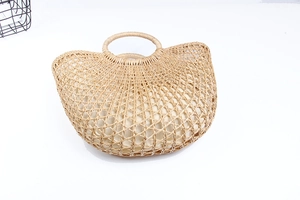 Detail of hand-woven semi-circular straw bag with hollow texture and sturdy round handles