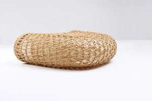 Detailed close-up of woven rattan texture and cream fabric lining on a crescent beach bag