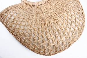 Detail of hollow-out weave pattern and soft fabric lining on beige straw handbag